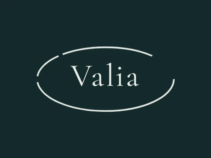 Marca del sello: una elipse abierta de trazo fino con el nombre Valia dentro, en hueso sobre verde profundo.